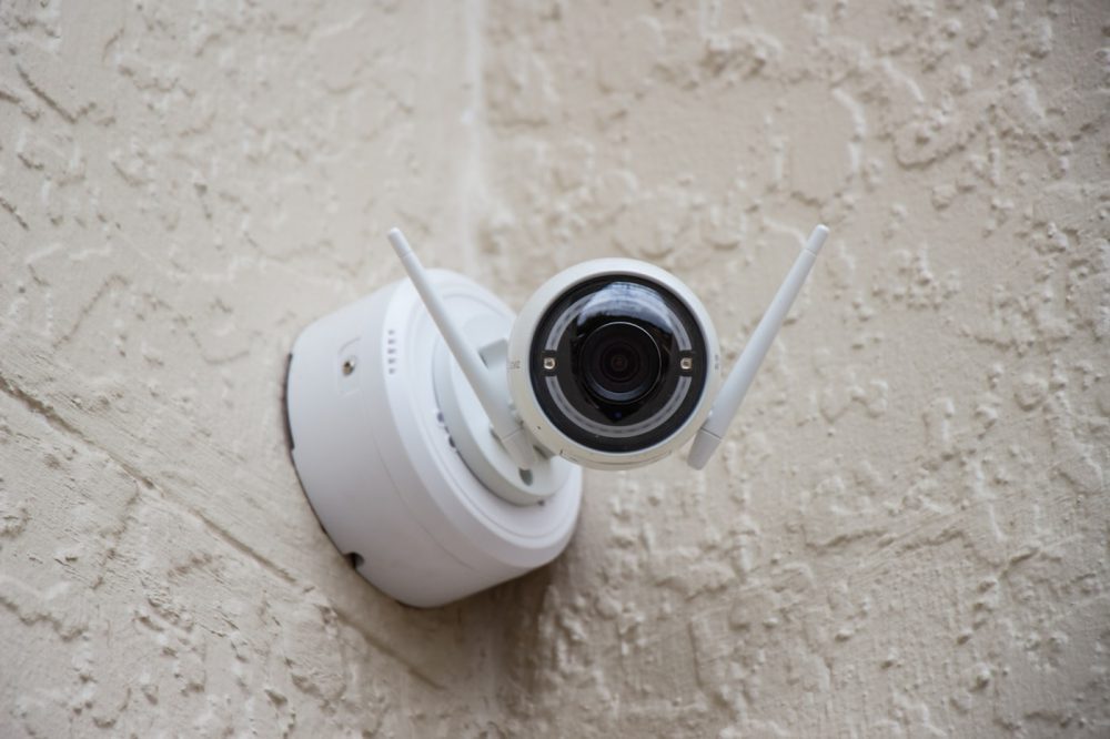 A single security camera watching a white wall
